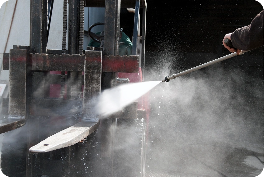 Forklift being cleaned with high-pressure hose